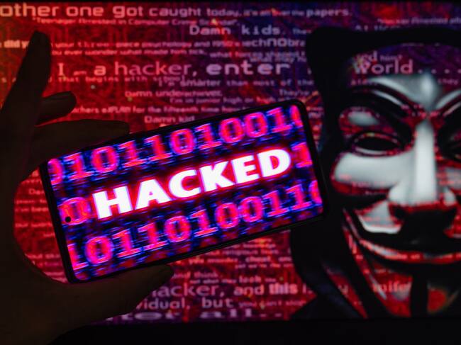 Hacked displayed on a mobile with binary code with in the background Anonymous mask. On 9 August 2023 in Brussels, Belgium. Jonathan Raa / Nurphoto (Photo by Jonathan Raa/NurPhoto via Getty Images)
