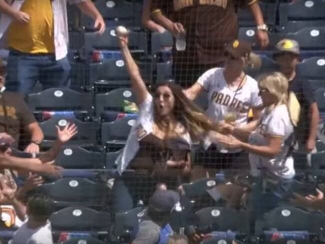 Mujer atrapa pelota de beisbol con bebé en brazos