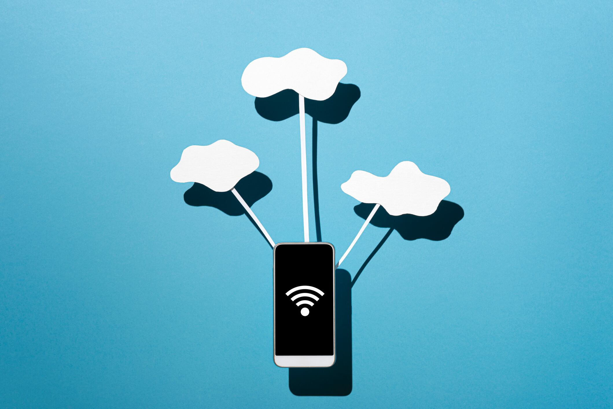 Clouds made with paper On blue Cardboard.Studio shot&quot;nSmartphone connected to clouds made of paper.Studio shot